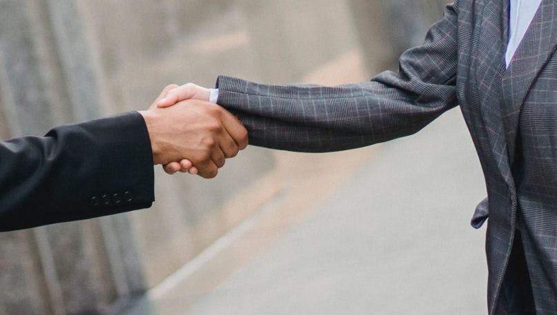 Two wearing suits shaking hands 